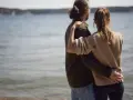 Par vid vattnet, en kvinna i sin bästa ålder med sexlust, omfamnar sin partner.