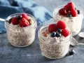Tre burkar med overnight oats recept, toppade med hallon och blåbär. En perfekt frukost att förbereda kvällen innan.