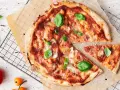 En läcker pizza med tomatsås, ost och färsk basilika. En bit är bortskuren, perfekt för att njuta av dess kalorier.