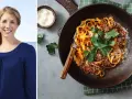 Glad kvinna ler vid havet. Bredvid en tallrik med fullkornspasta nyttigt, toppad med köttfärssås och persilja.