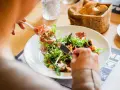 En person äter en sallad med skinka, en del av en 800 kcal diet. Brödkorg i bakgrunden.
