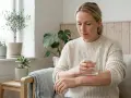 Kvinna med utslag på armen, som kan vara ett av sepsis symtom, håller ett glas vatten.