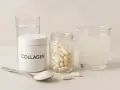 En burk med kollagenpulver, en sked med pulver, en burk med kollagenkapslar och ett glas med kollagendryck. Allt för en stark mage.