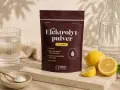 En påse elektrolytpulver med citron, bredvid färska citroner, ett glas vatten och en skål med pulver. Perfekt för att motverka elektrolytbrist.