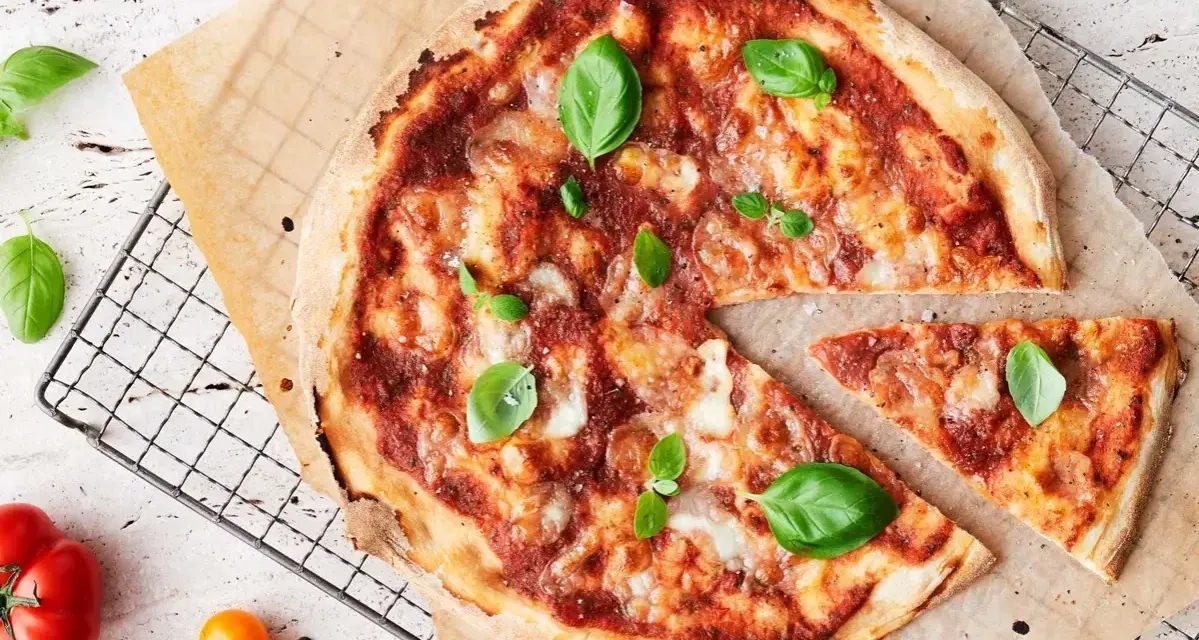 En läcker pizza med tomatsås, ost och färsk basilika. En bit är bortskuren, perfekt för att njuta av dess kalorier.