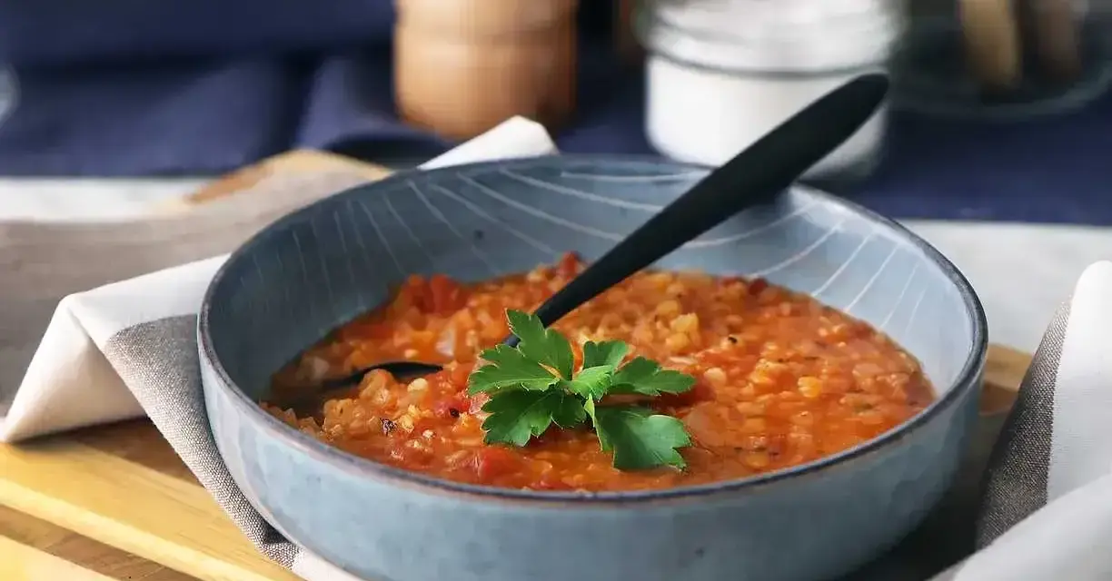 En värmande linssoppa, perfekt för dig som vill gå ner i vikt. Serveras i en blå skål med en persiljekvist.