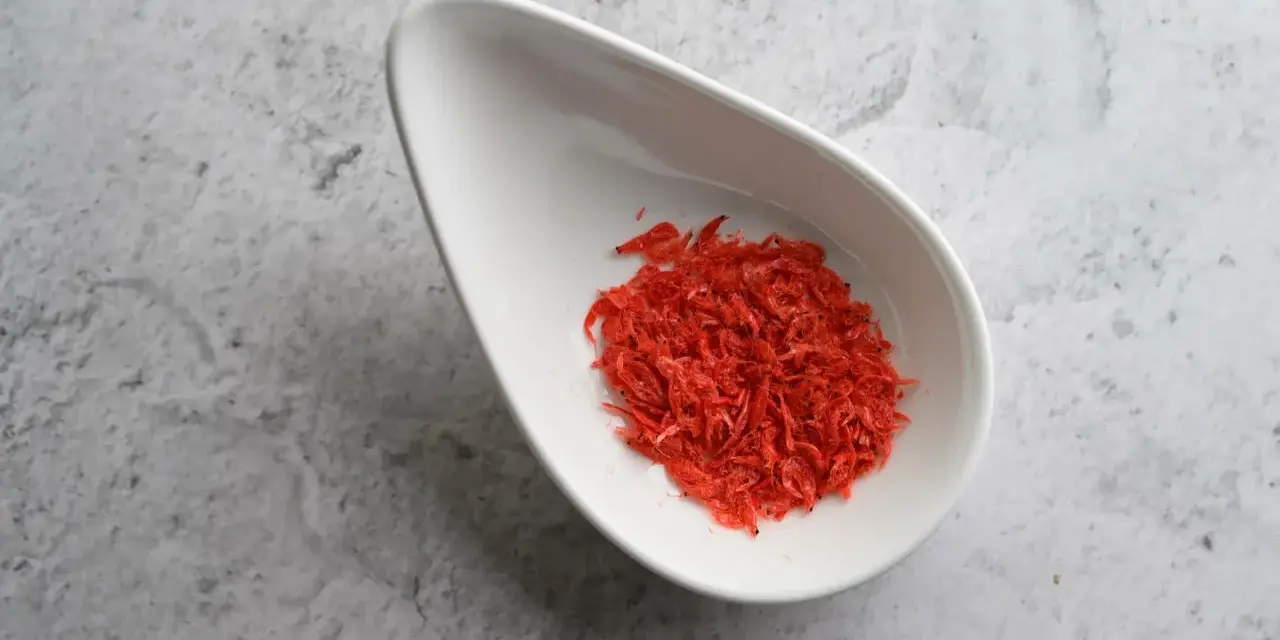 Torkade räkor i en vit skål, en källa till astaxanthin. Undrar du över astaxanthin biverkningar?