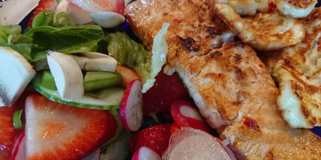 En härlig sallad med grillad lax, halloumi, jordgubbar, rädisor och grönsaker. En perfekt sommarmåltid!