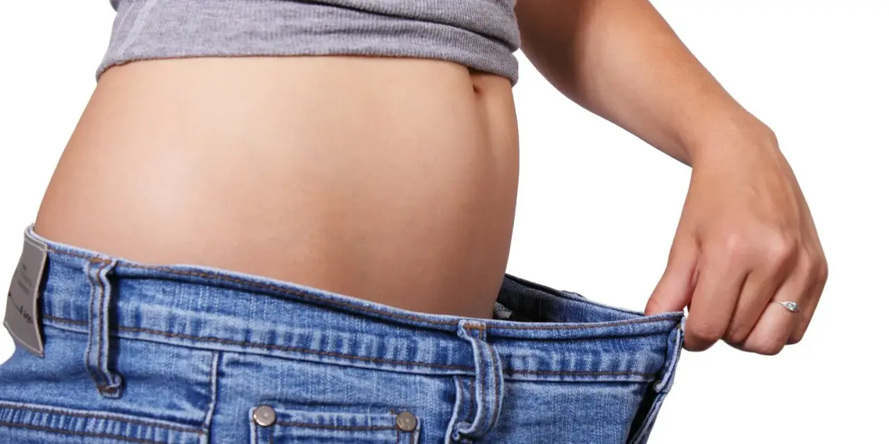 En person visar hur stora jeansen blivit efter viktnedgång. Ibland är det svårt att gå ner i vikt hormoner kan spela roll.