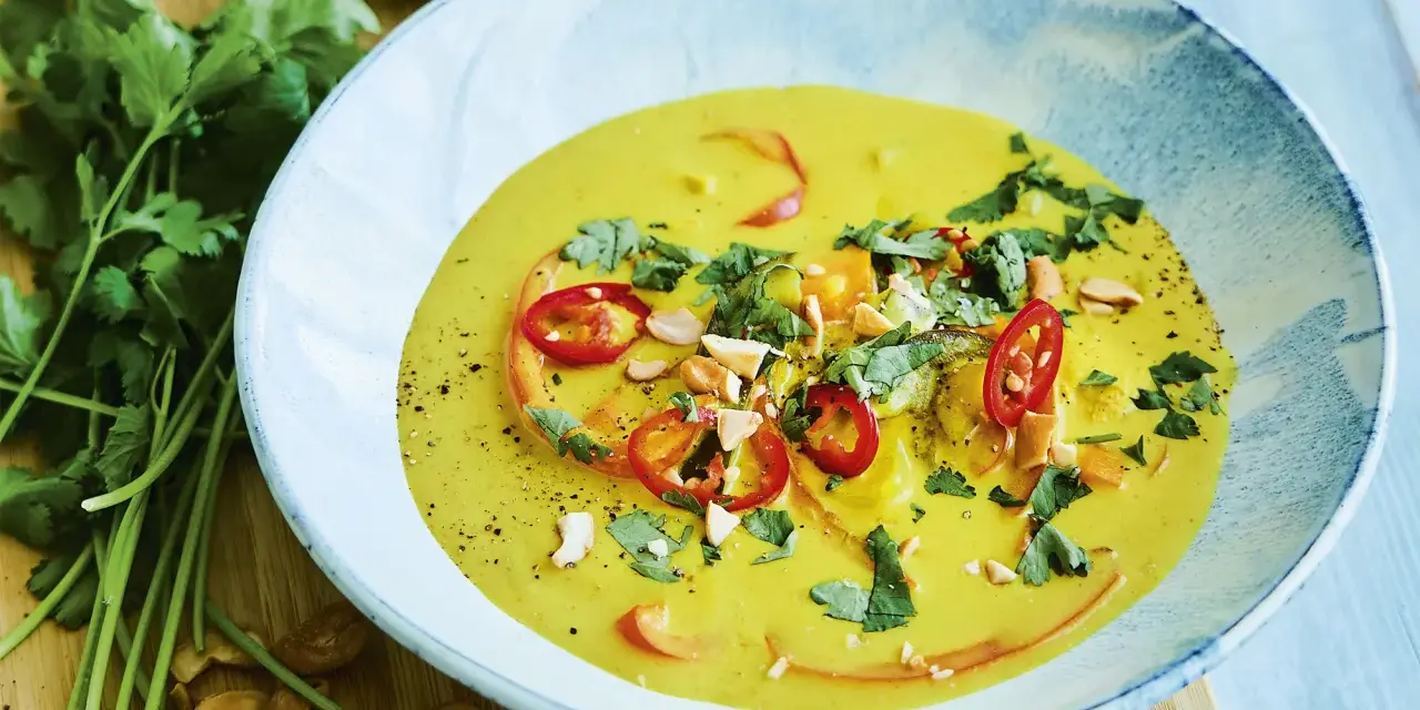 En krämig kycklingpaj med curry, toppad med chili, koriander och cashewnötter. Serveras i en vacker blåvit skål.