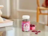 D-vitamin jordgubbssmak för barn. En burk med rosa etikett och en apa, bredvid en rosa skål med hjärtformade gummies.