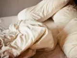 Ovanpå en bädd med vita lakan och kuddar, en påminnelse om att sömnmedel som melatonin kan ge biverkningar.