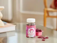 D-vitamin jordgubbssmak för barn. En burk med rosa etikett och en apa, bredvid en rosa skål med hjärtformade gummies.