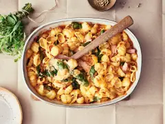 En krämig pastarätt med spenat och lax, perfekt för nyttiga recept. En träsked lyfter upp en portion ur ugnsformen.