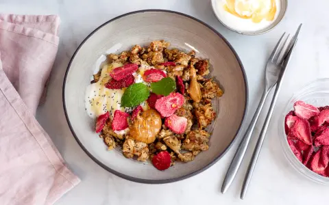 En skål med granola, yoghurt, jordgubbar och jordnötssmör. En perfekt nyttig frukost för en bra start på dagen.