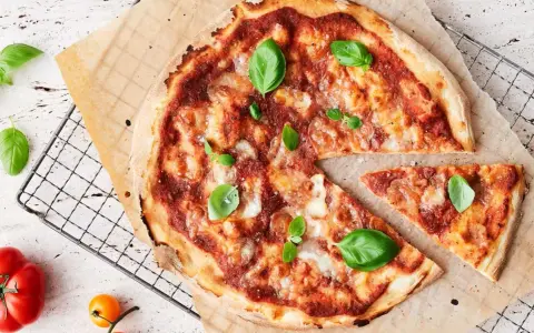 En läcker pizza med tomatsås, ost och färsk basilika. En bit är bortskuren, perfekt för att njuta av dess kalorier.