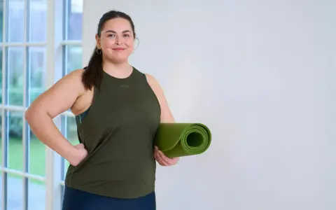 En kvinna med träningskläder och en grön yogamatta redo att kickstarta viktnedgång.