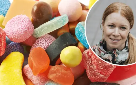 En kvinna ler bredvid en hög med godis. Kanske är det dags att rensa kroppen från socker?