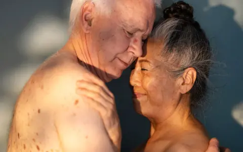 Ett äldre par omfamnar varandra ömt, deras ansikten nära varandra. Ljuset faller mjukt över dem och framhäver deras hud. Kärlek och närhet lyser igenom, en påminnelse om att bra sex kan finnas i alla åldrar.