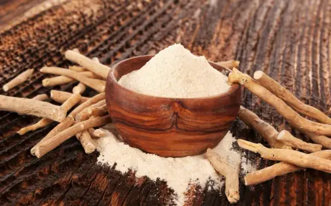 Ashwagandha-pulver i en träskål omgivet av rötter. Ett naturligt stöd för kvinnor under klimakteriet.