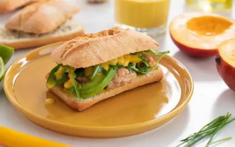 En kycklingsmörgås med avokado och rucola, generöst toppad med en krämig mango dressing.
