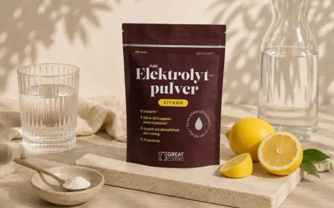 En påse elektrolytpulver med citron, bredvid färska citroner, ett glas vatten och en skål med pulver. Perfekt för att motverka elektrolytbrist.