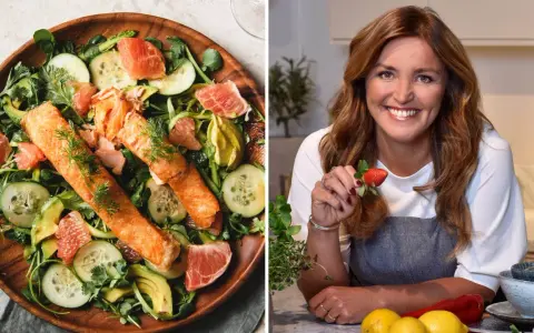 En kvinna med jordgubbe i handen och en fräsch lax- och avokadosallad. Recept för att gå ner 2 kg i veckan.
