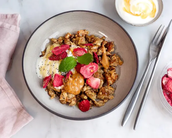 En skål med granola, yoghurt, jordgubbar och jordnötssmör. En perfekt nyttig frukost för en bra start på dagen.
