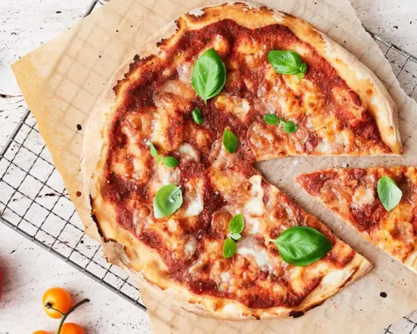 En läcker pizza med tomatsås, ost och färsk basilika. En bit är bortskuren, perfekt för att njuta av dess kalorier.