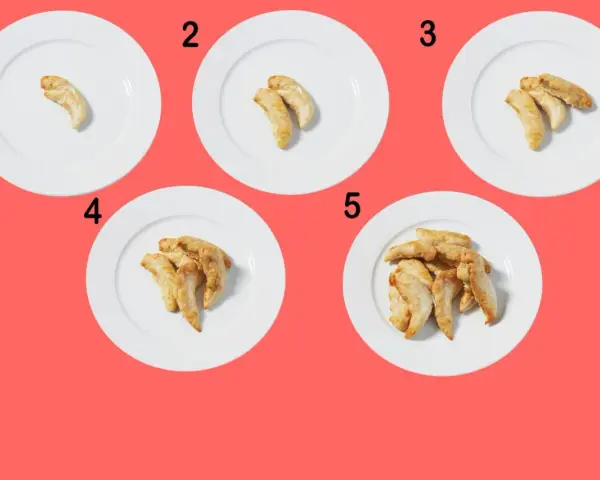 Fem tallrikar med ökande mängd kycklingbitar, från en till flera. En visuell guide för att förstå kyckling kalorier i olika portionsstorlekar.