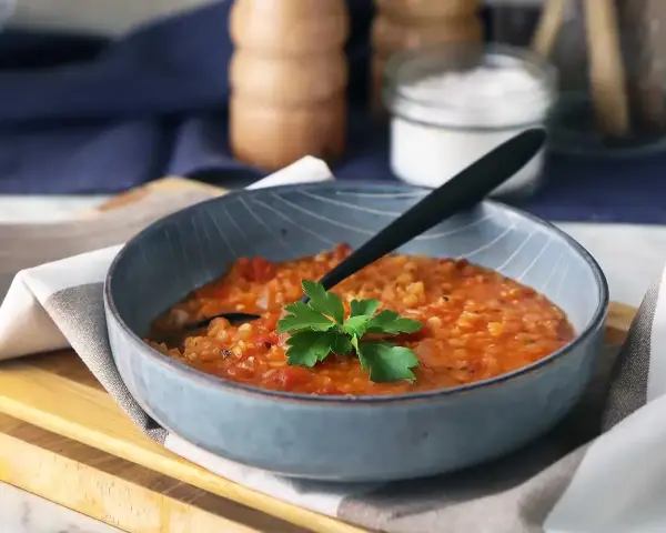 En värmande linssoppa, perfekt för dig som vill gå ner i vikt. Serveras i en blå skål med en persiljekvist.