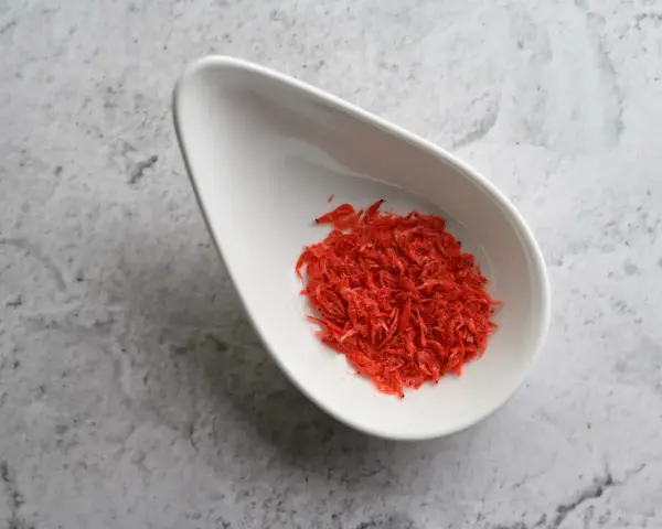 Torkade räkor i en vit skål, en källa till astaxanthin. Undrar du över astaxanthin biverkningar?
