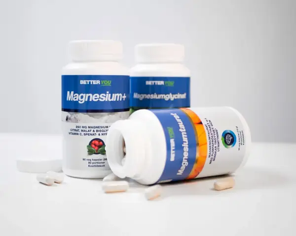 Flera burkar kosttillskott från Better You, inklusive Magnesium+ och Magnesiumtaurat. En burk med magnesiumtaurat ligger framför, med kapslar utspridda. Kan hjälpa mot extraslag.
