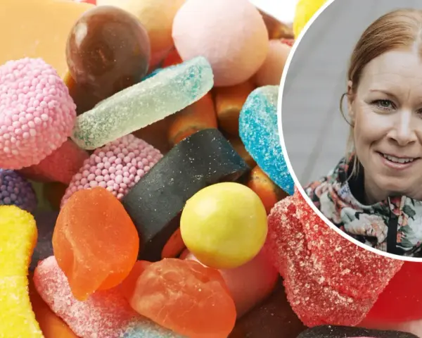 En kvinna ler bredvid en hög med godis. Kanske är det dags att rensa kroppen från socker?