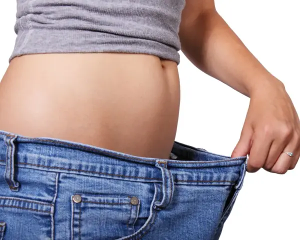 En person visar hur stora jeansen blivit efter viktnedgång. Ibland är det svårt att gå ner i vikt hormoner kan spela roll.