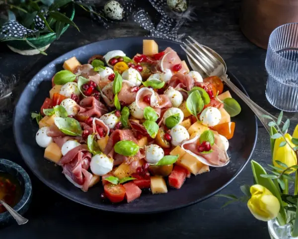 En läcker melonsallad med mozzarella, prosciutto, granatäpple och färsk basilika. En perfekt sommarrätt!