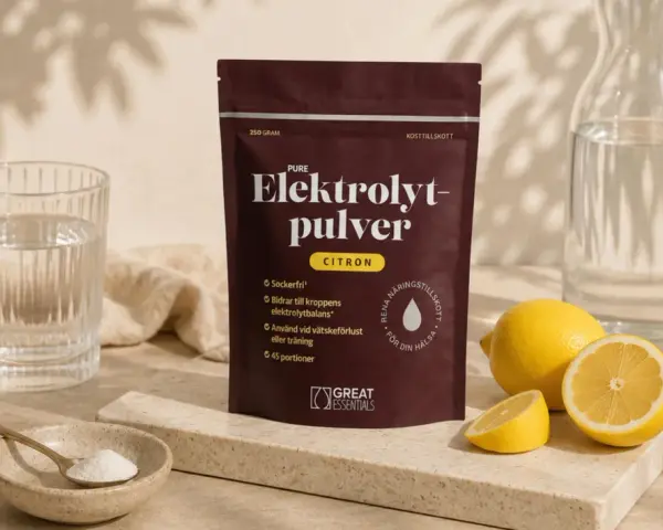En påse elektrolytpulver med citron, bredvid färska citroner, ett glas vatten och en skål med pulver. Perfekt för att motverka elektrolytbrist.