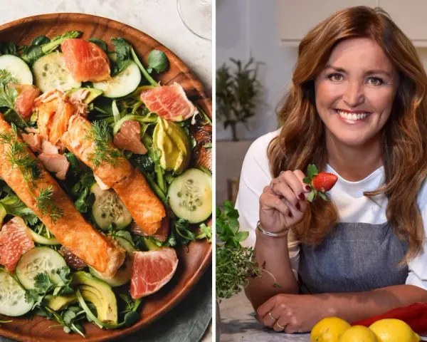 En kvinna med jordgubbe i handen och en fräsch lax- och avokadosallad. Recept för att gå ner 2 kg i veckan.