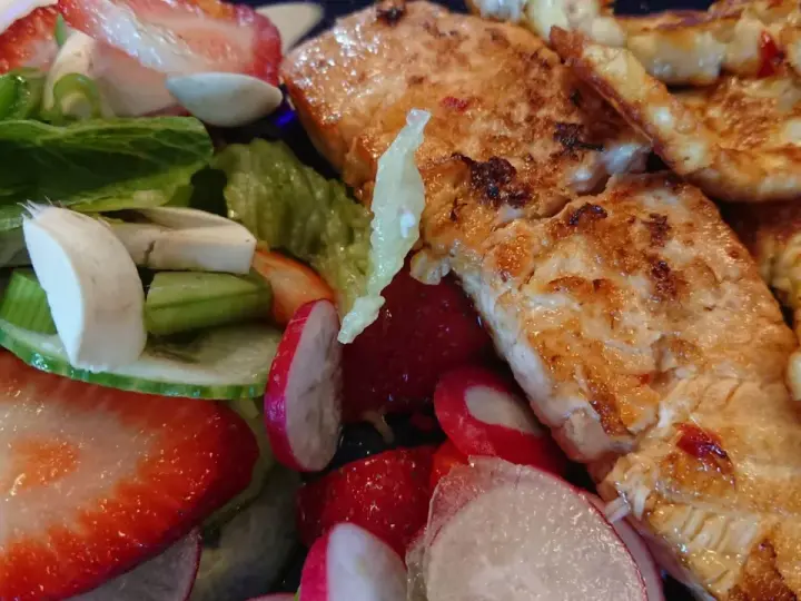 En härlig sallad med grillad lax, halloumi, jordgubbar, rädisor och grönsaker. En perfekt sommarmåltid!