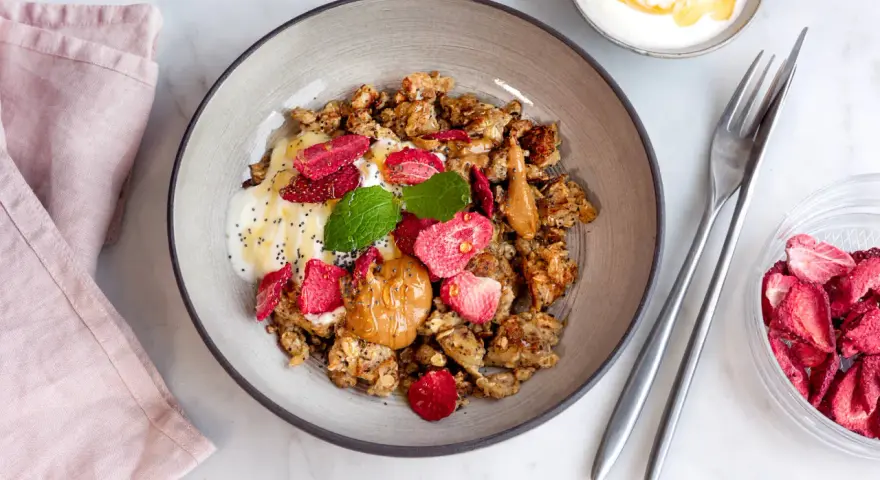 En skål med granola, yoghurt, jordgubbar och jordnötssmör. En perfekt nyttig frukost för en bra start på dagen.