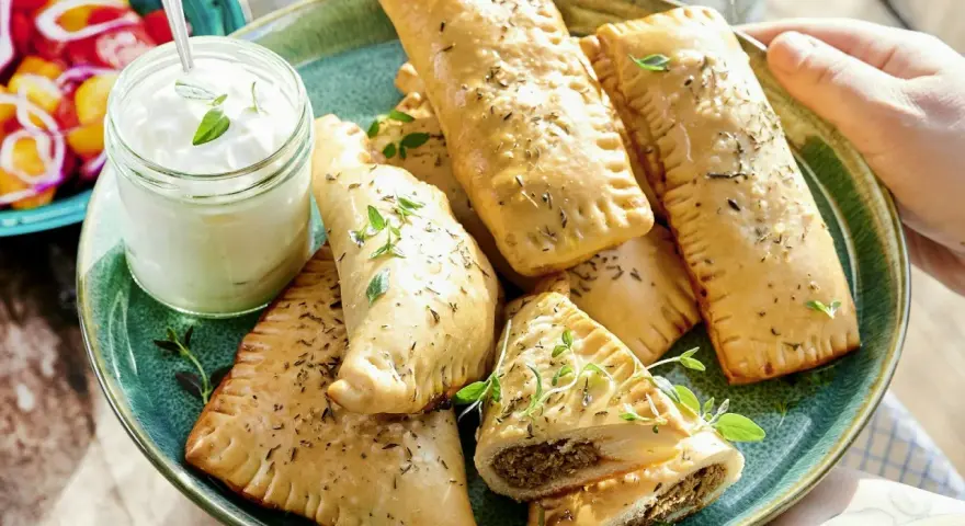 En tallrik med gyllene piroger, perfekta som mellanmål för barn. Serveras med en klick krämig dipp och färska örter.