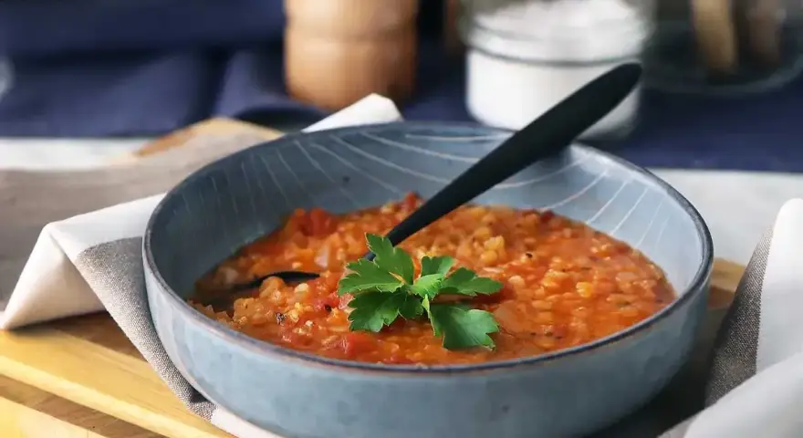 En värmande linssoppa, perfekt för dig som vill gå ner i vikt. Serveras i en blå skål med en persiljekvist.