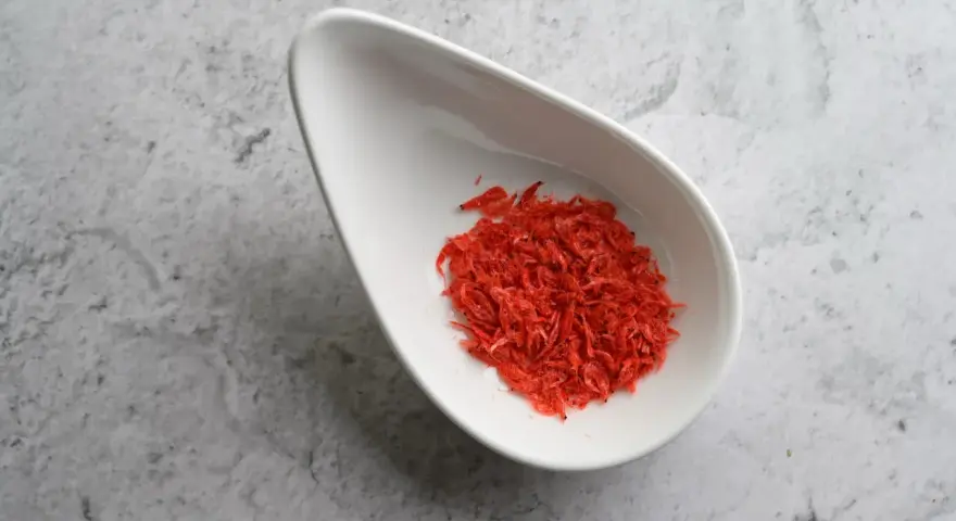 Torkade räkor i en vit skål, en källa till astaxanthin. Undrar du över astaxanthin biverkningar?
