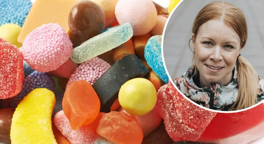 En kvinna ler bredvid en hög med godis. Kanske är det dags att rensa kroppen från socker?