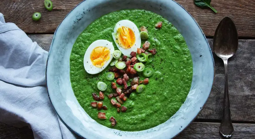 En krämig spenat och broccolisoppa toppad med ägg, knaperstekt bacon och salladslök. En härlig och näringsrik måltid.