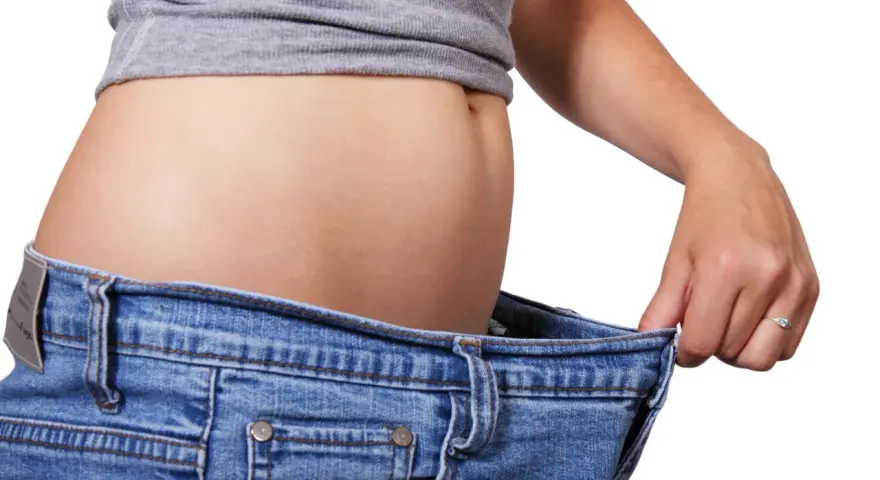 En person visar hur stora jeansen blivit efter viktnedgång. Ibland är det svårt att gå ner i vikt hormoner kan spela roll.