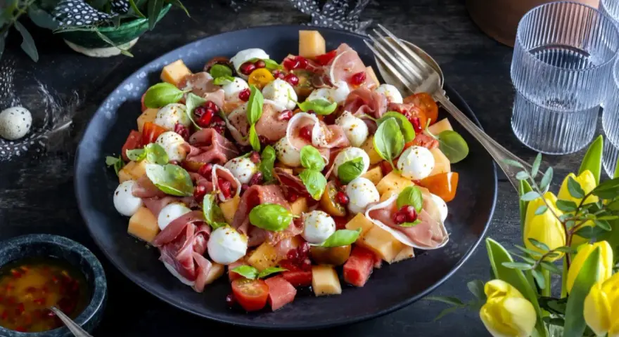En läcker melonsallad med mozzarella, prosciutto, granatäpple och färsk basilika. En perfekt sommarrätt!