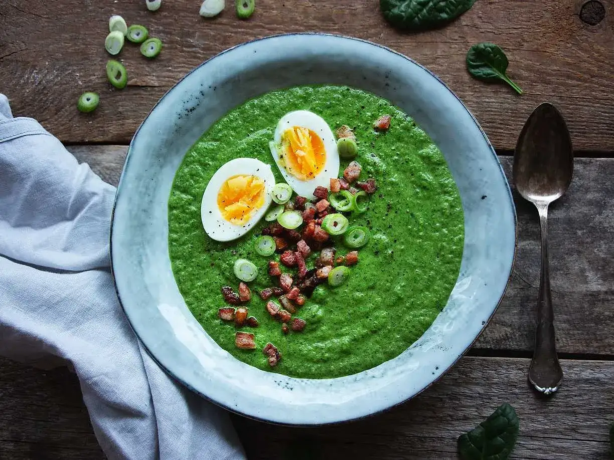 En krämig spenat och broccolisoppa toppad med ägg, knaperstekt bacon och salladslök. En härlig och näringsrik måltid.