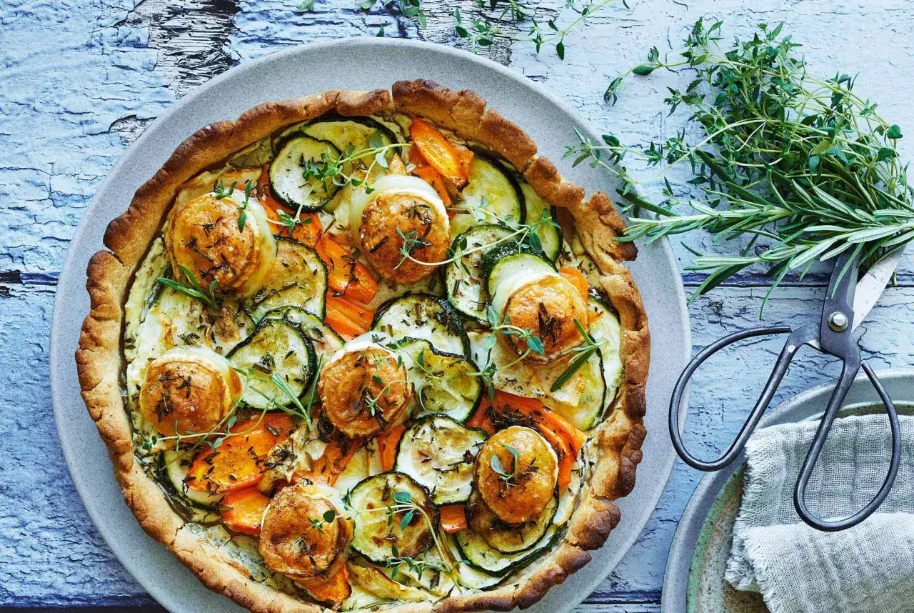 En vacker, kalorisnål paj fylld med zucchini, morötter och getost, toppad med färska örter.