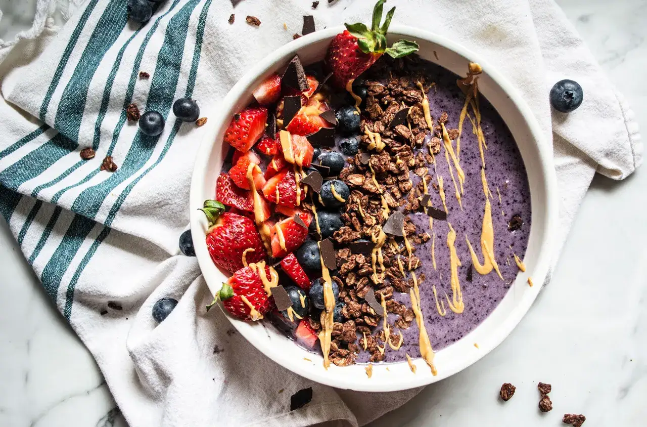 En h&auml;rlig smoothie bowl med jordgubbar, bl&aring;b&auml;r, granola och choklad. Perfekt antiinflammatorisk kost frukost f&ouml;r en energifylld start p&aring; dagen.